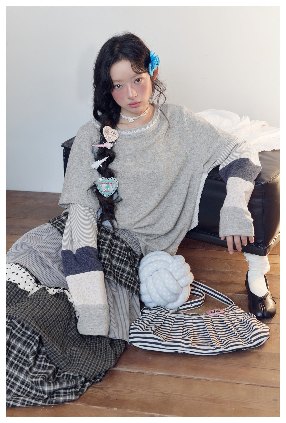 Model seated on the floor wearing the gray layered-look top with lace neckline and color-block striped sleeves