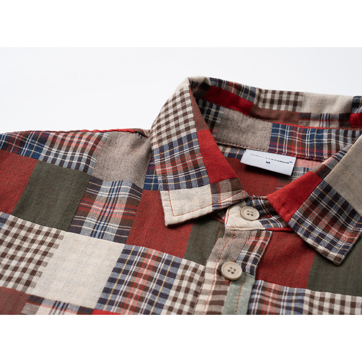 Close-up of a red, cream, navy, and olive patchwork plaid shirt collar and button placket.