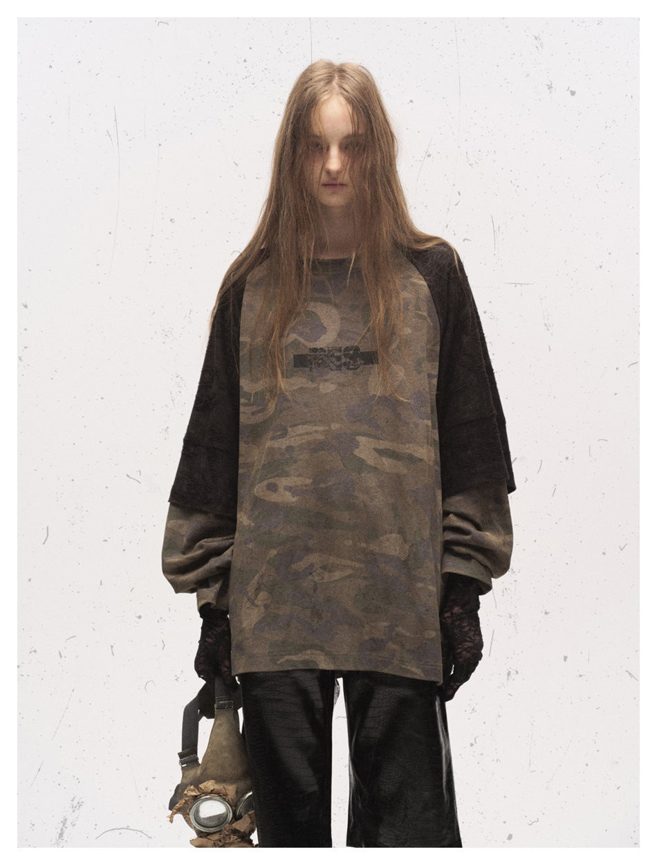 Front view of a model in an oversized brown camouflage raglan shirt with black sleeves and black shorts.