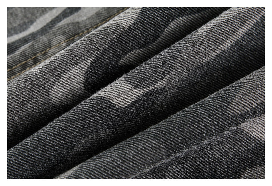 Macro view of the dark gray camouflage denim’s diagonal twill texture and folds.