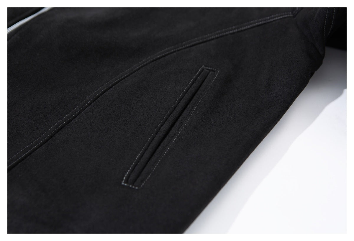 Close-up of a black jacket with a narrow welt pocket and curved seam stitching.