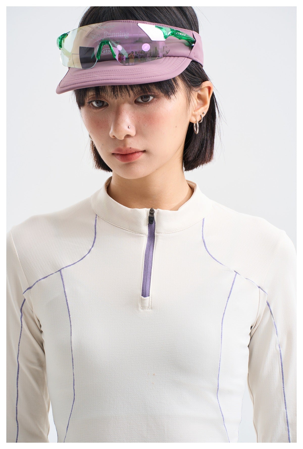 Model wearing a white long-sleeve quarter-zip top with a stand collar and curved purple seam lines.