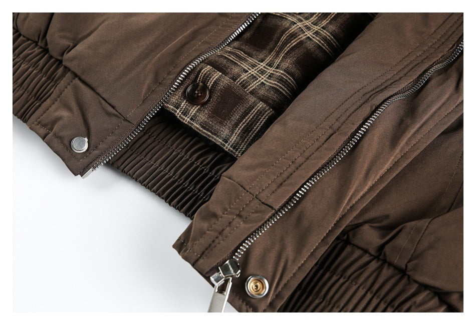 Close-up of a brown jacket with a metal zipper, snap fastener, elasticized hem and brown plaid lining.