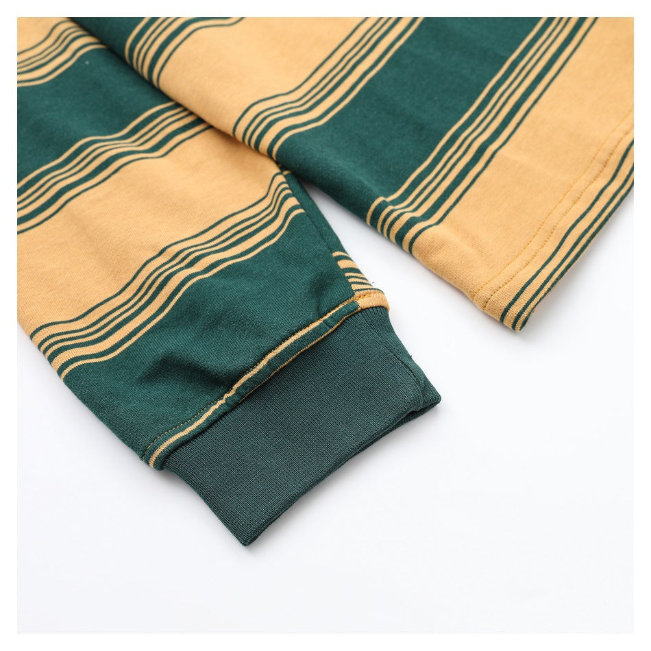 Close-up of a dark green sleeve with mustard-yellow stripes and a solid dark green cuff.