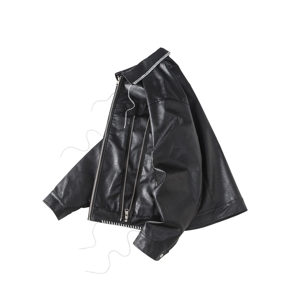 Angled front view of a black jacket with zip details, white contrast stitching, and loose decorative threads.