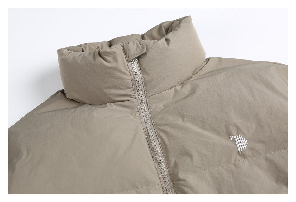 Close-up of a taupe padded jacket collar, front zipper, and small white embroidered chest mark.