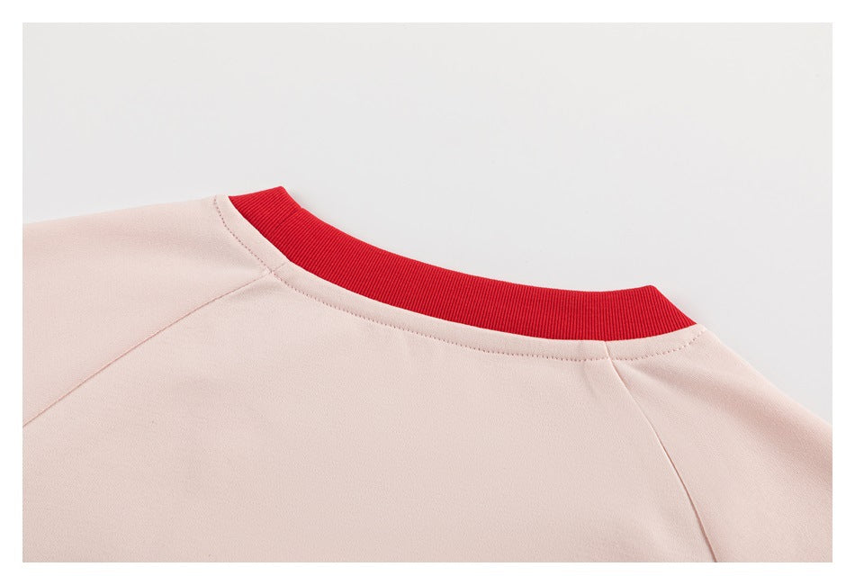 Close-up of a pale pink neckline with a bright red ribbed collar and shoulder seams.