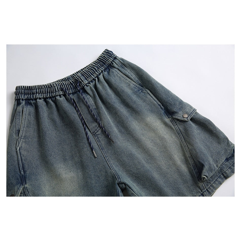 Flat lay front view of blue-gray denim shorts with an elastic drawstring waist and buttoned side flap pocket.