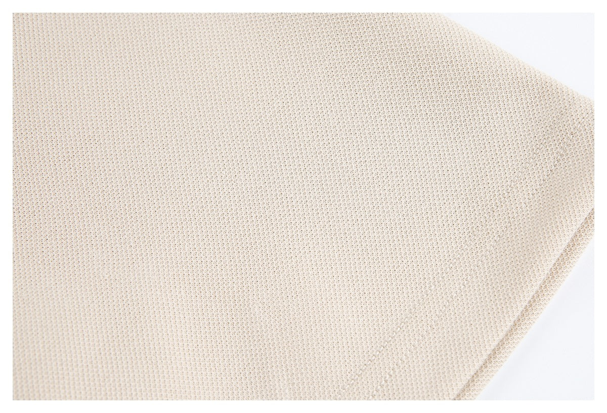 Close-up of cream-beige textured fabric with a curved stitched edge.