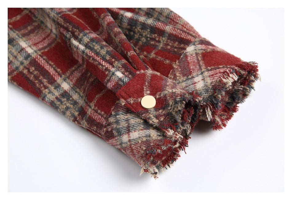 Close-up of a plaid sleeve cuff with a pale button and frayed edges.