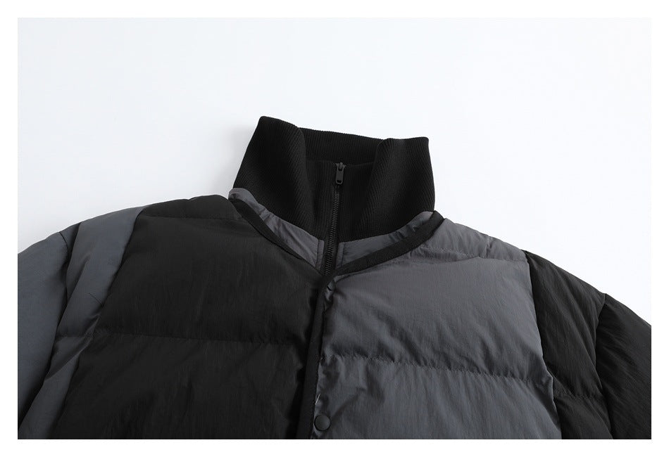 Close-up of a black and charcoal puffer jacket’s ribbed stand collar, zipper, and color-blocked front.