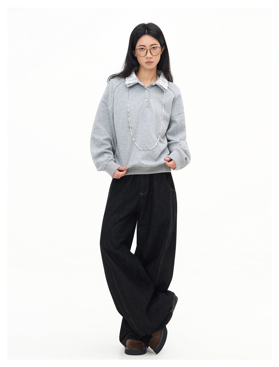 Full-length front view of a model wearing a light gray collared pullover and black wide-leg jeans.