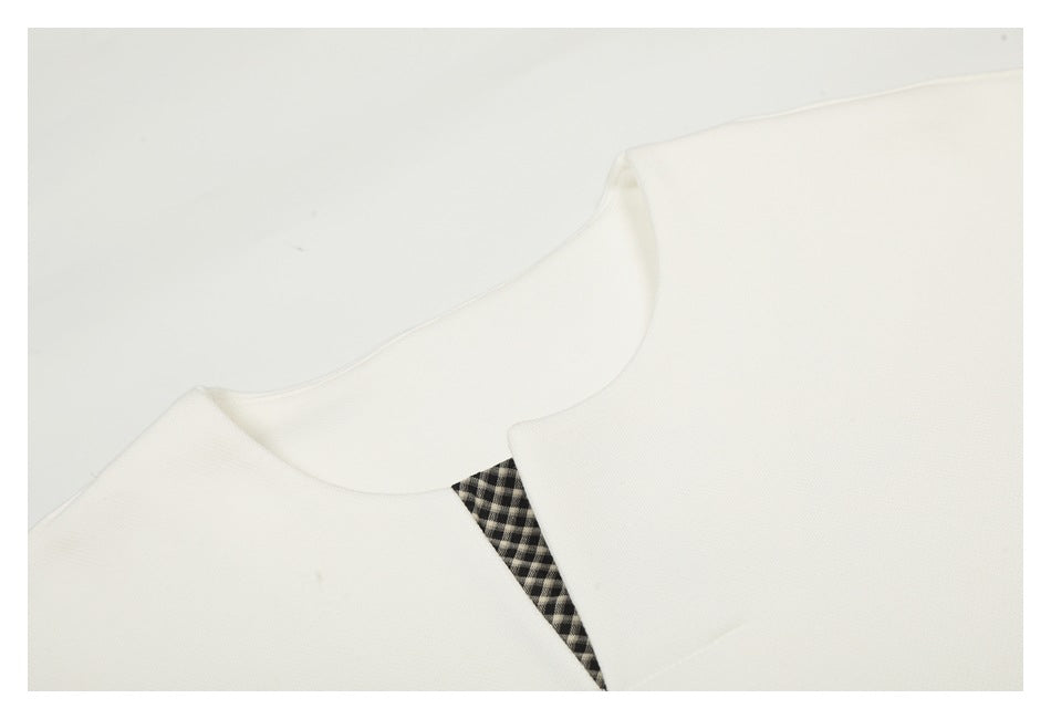 Close-up of a white sweatshirt neckline with a small black-and-white checked V-shaped insert.