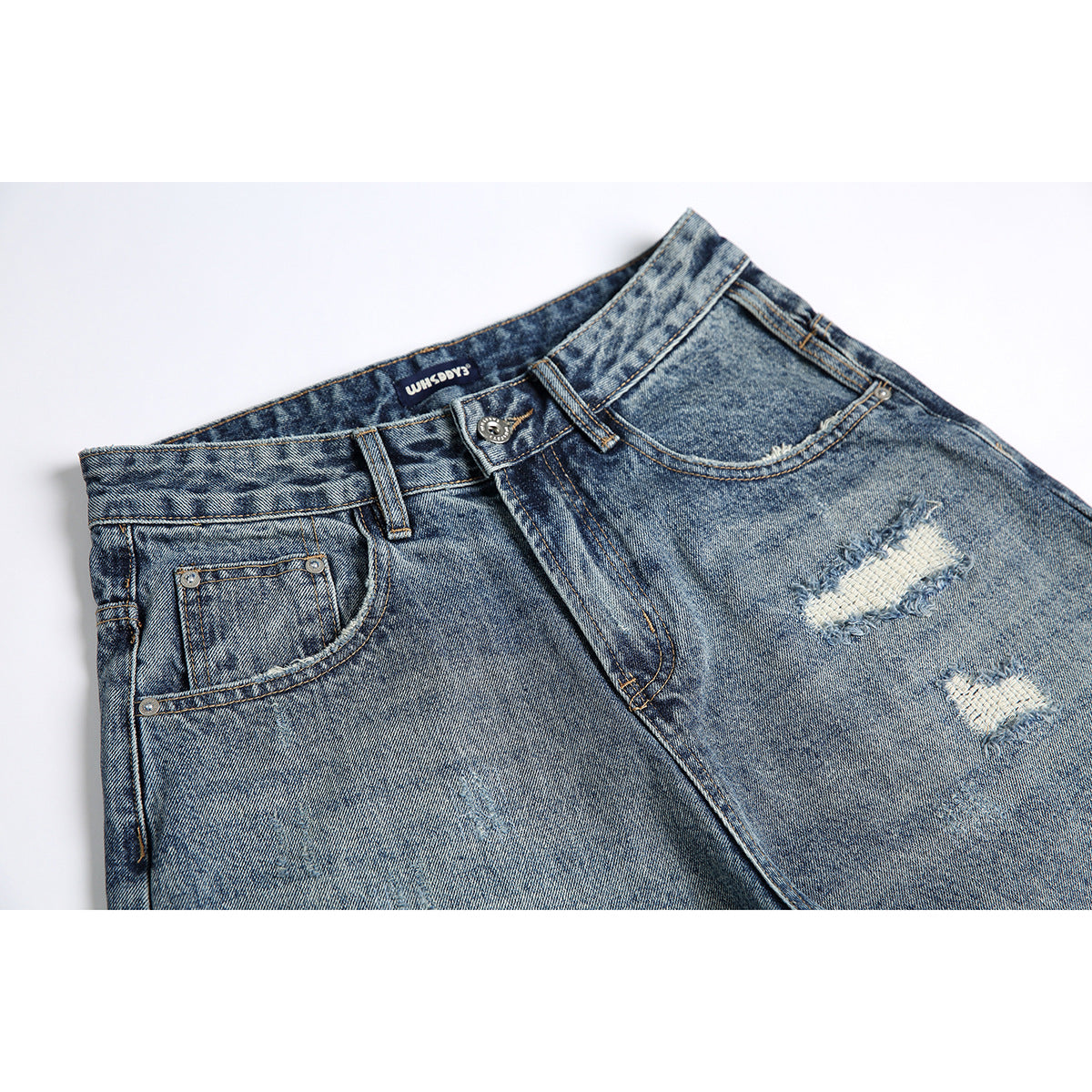 Close-up of blue acid-wash jeans showing the front waistband, pockets, button, and distressed thigh patches.