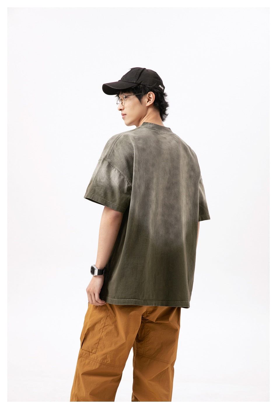 Model shown from behind wearing an oversized olive-gray short-sleeve T-shirt with dropped shoulders.