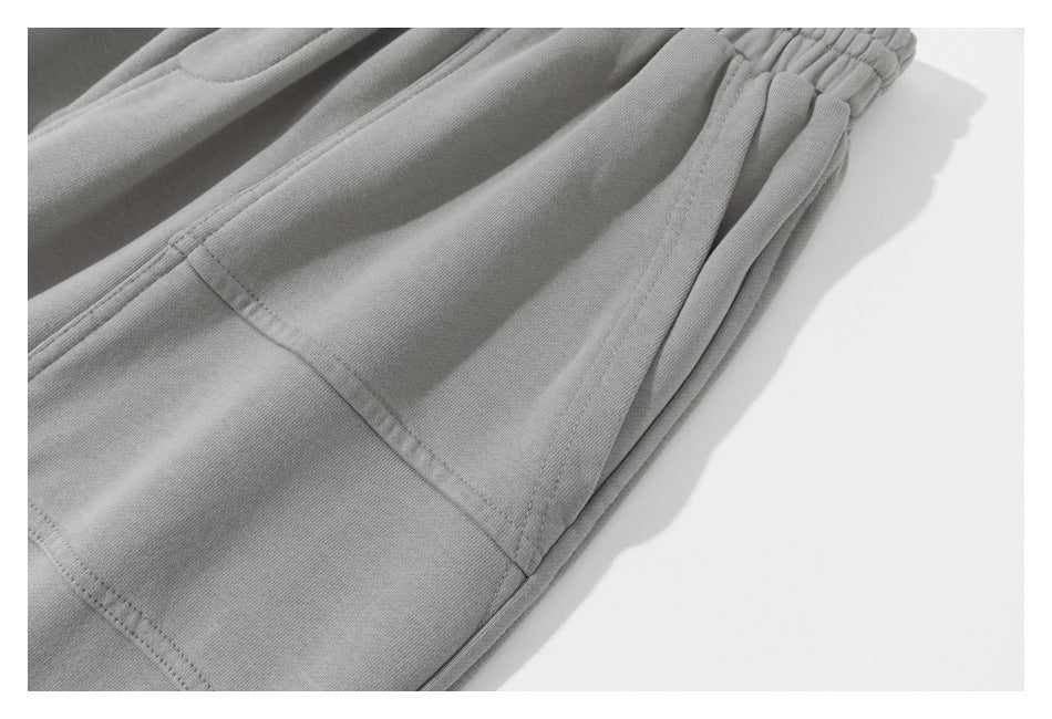 Close-up of gray sweatpants showing a side seam and gathered elastic waistband.