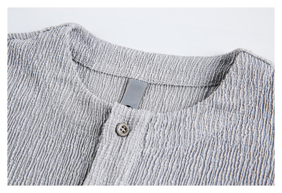 Close-up of a light gray textured shirt collar and button placket with one button.