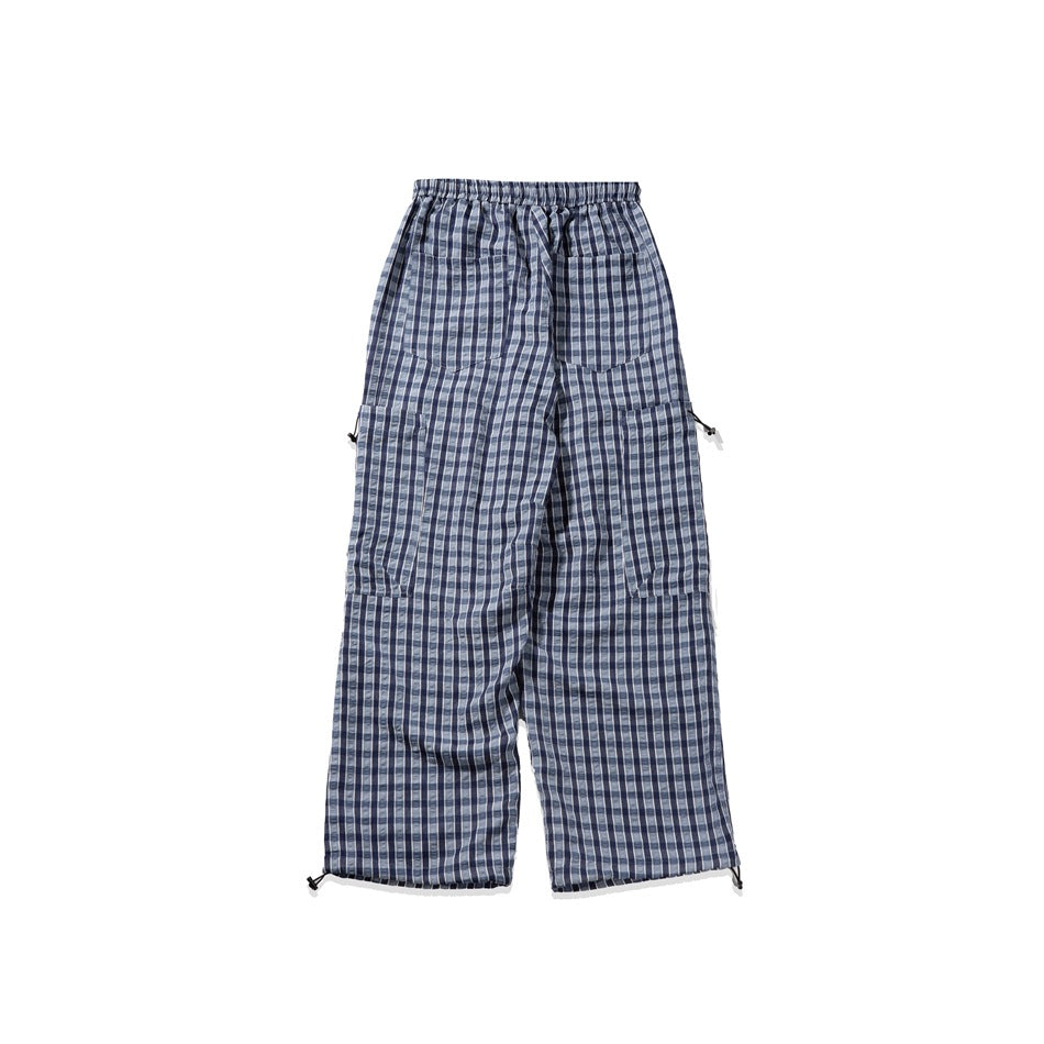 Full view of blue and gray plaid pants from the back, with an elastic waistband, patch pockets, and hem toggles.