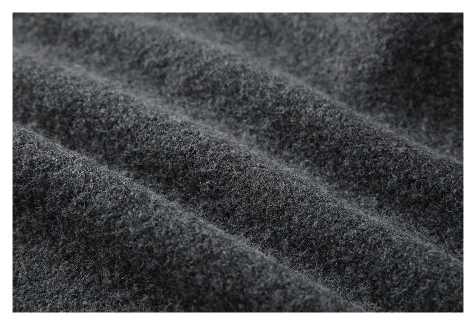 Macro view of dark charcoal fuzzy knit fabric arranged in soft folds.
