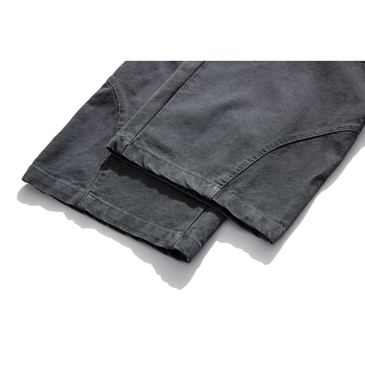 Close-up of charcoal-gray trouser hems with curved panel seams and visible stitching.