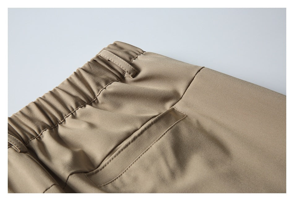 Close-up of the back waistband and welt pocket on beige trousers.