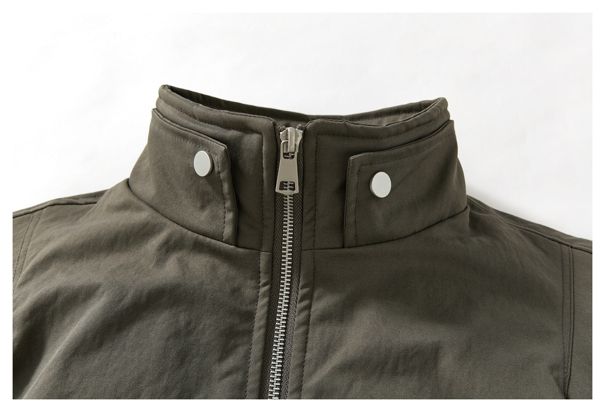 Close-up of a dark olive jacket's raised collar, center zipper, and two snap-button tabs.