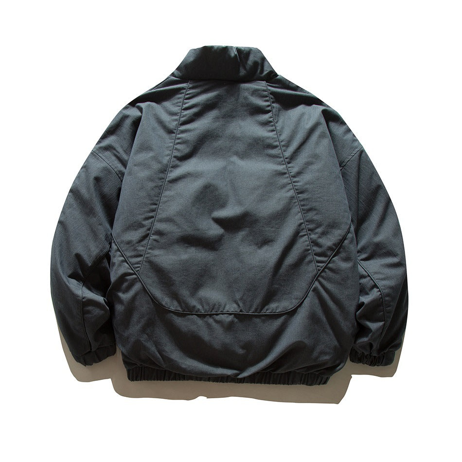 Back view of dark navy-gray jacket with curved panel seams, stand collar and elastic hem and cuffs, flat lay