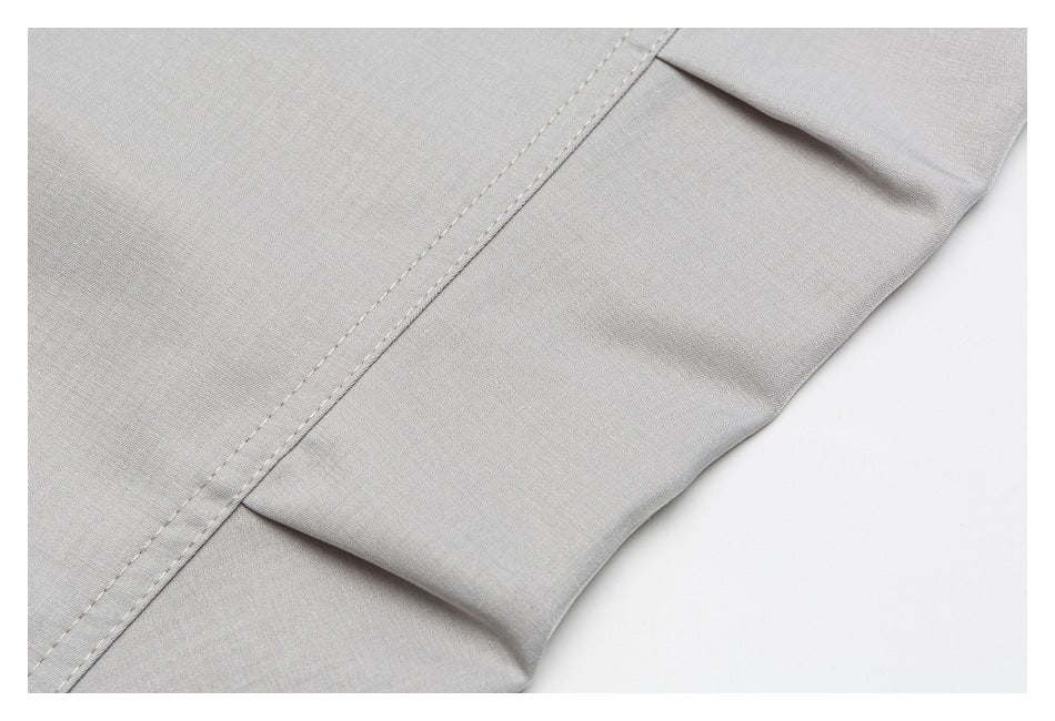 Close-up of a light-gray garment seam and folded hem with visible stitching.