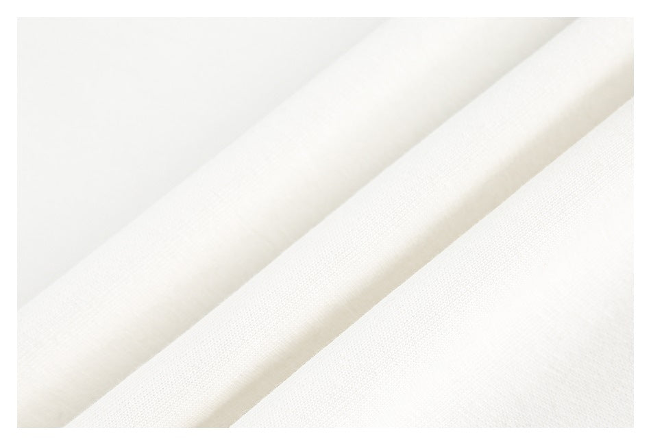 Macro view of white garment fabric arranged in soft diagonal folds, showing its surface texture.