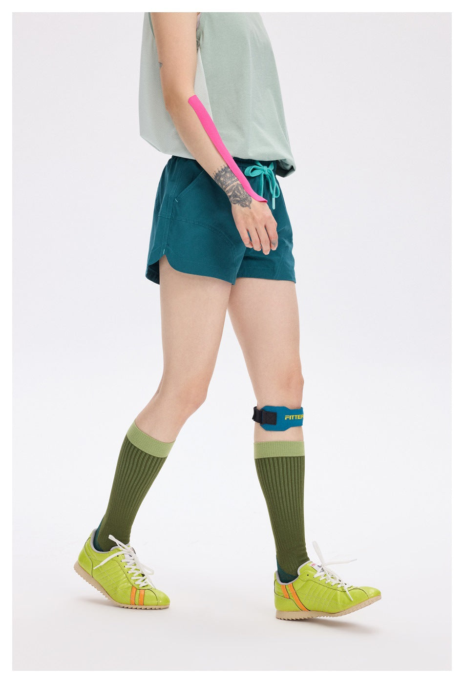 Side view of a model wearing teal running shorts with curved pockets and a turquoise waist drawstring.