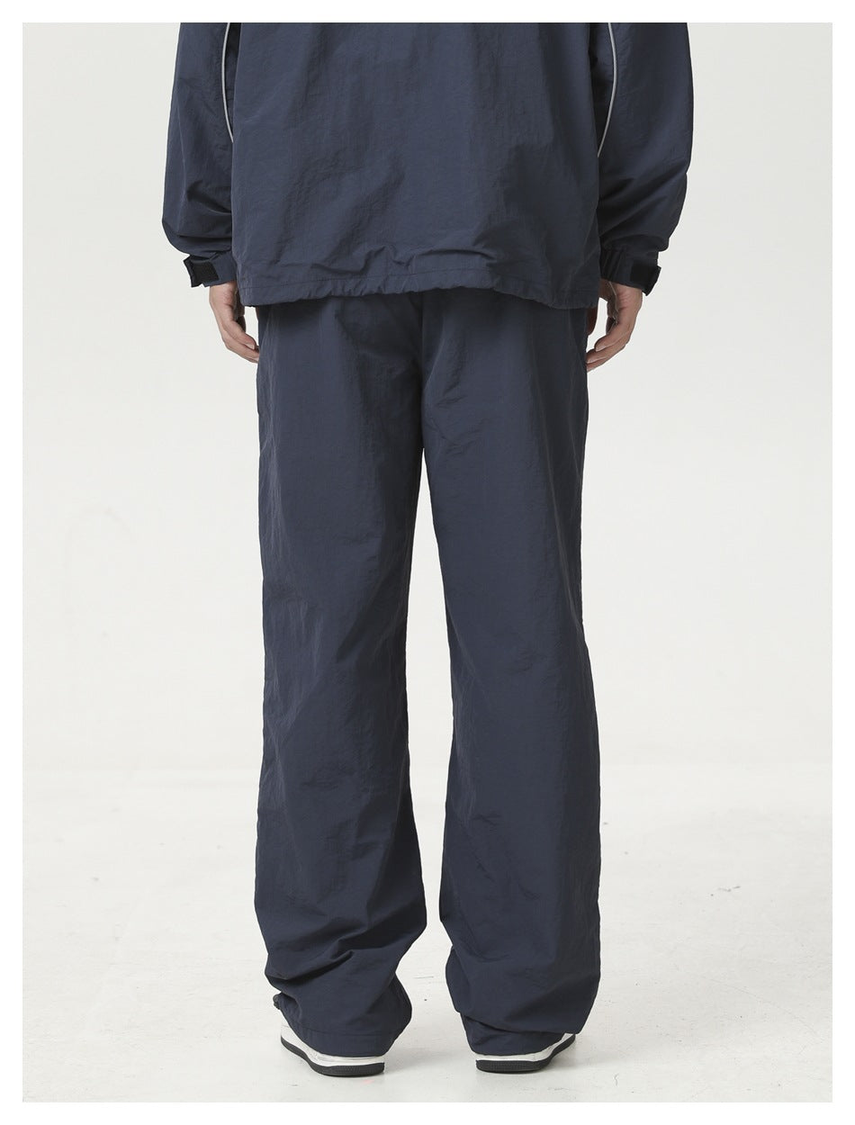 Cropped back view of a model wearing loose navy pants beneath a matching jacket.