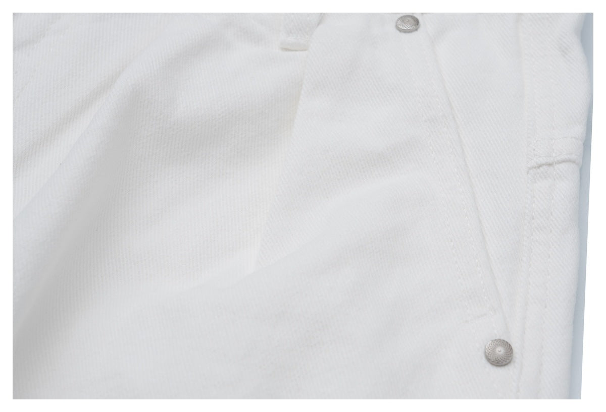 Close-up of white jeans showing the waistband, front pocket area, and silver rivets.