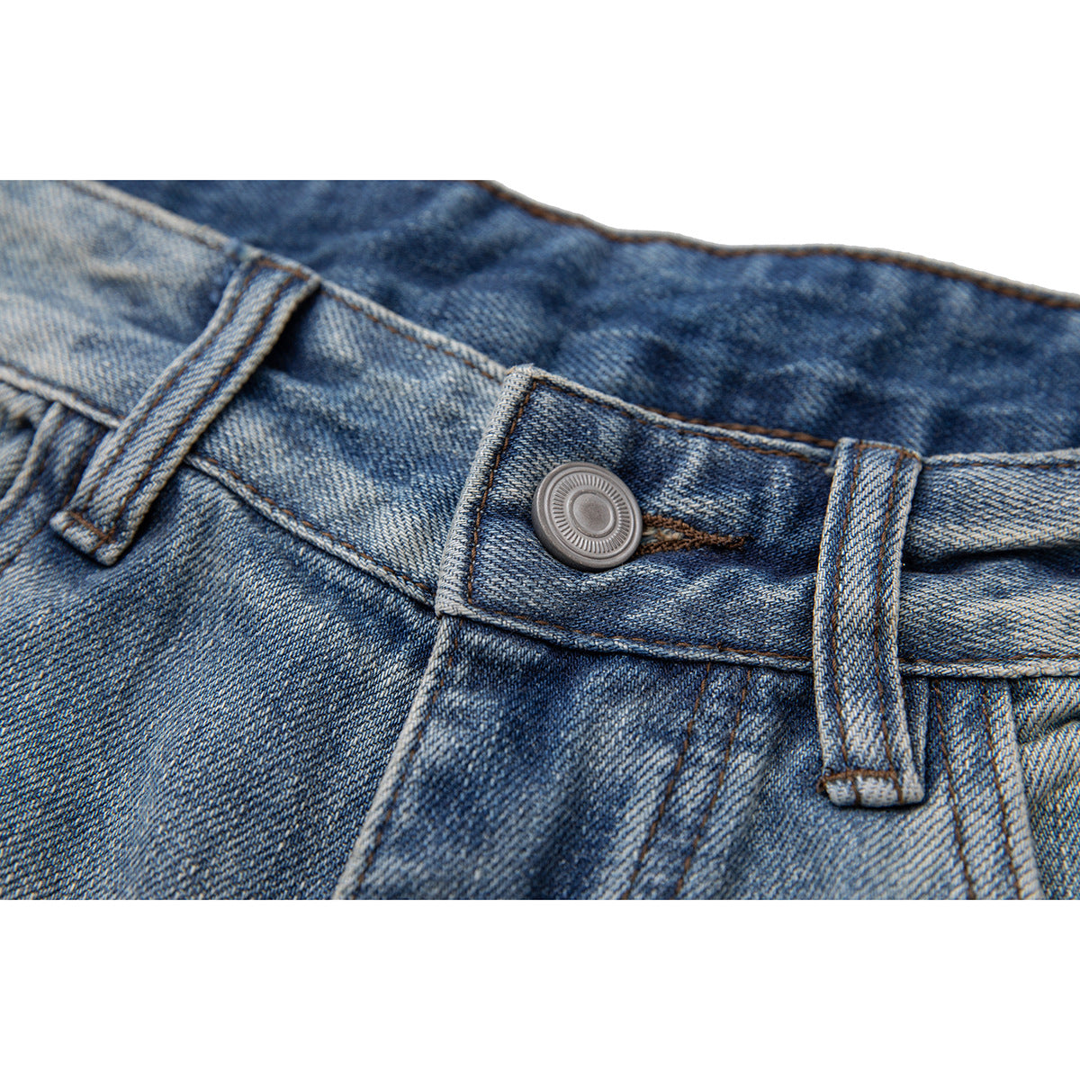 Close-up of blue washed jeans showing the waistband, belt loops, and metal button.