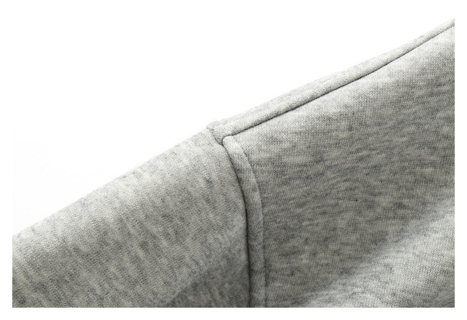 Close-up of a shoulder seam on light heather-gray fabric against a white background.