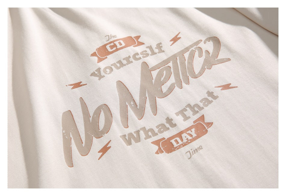 Close-up of the shirt’s distressed brown and tan English text graphic on cream fabric.