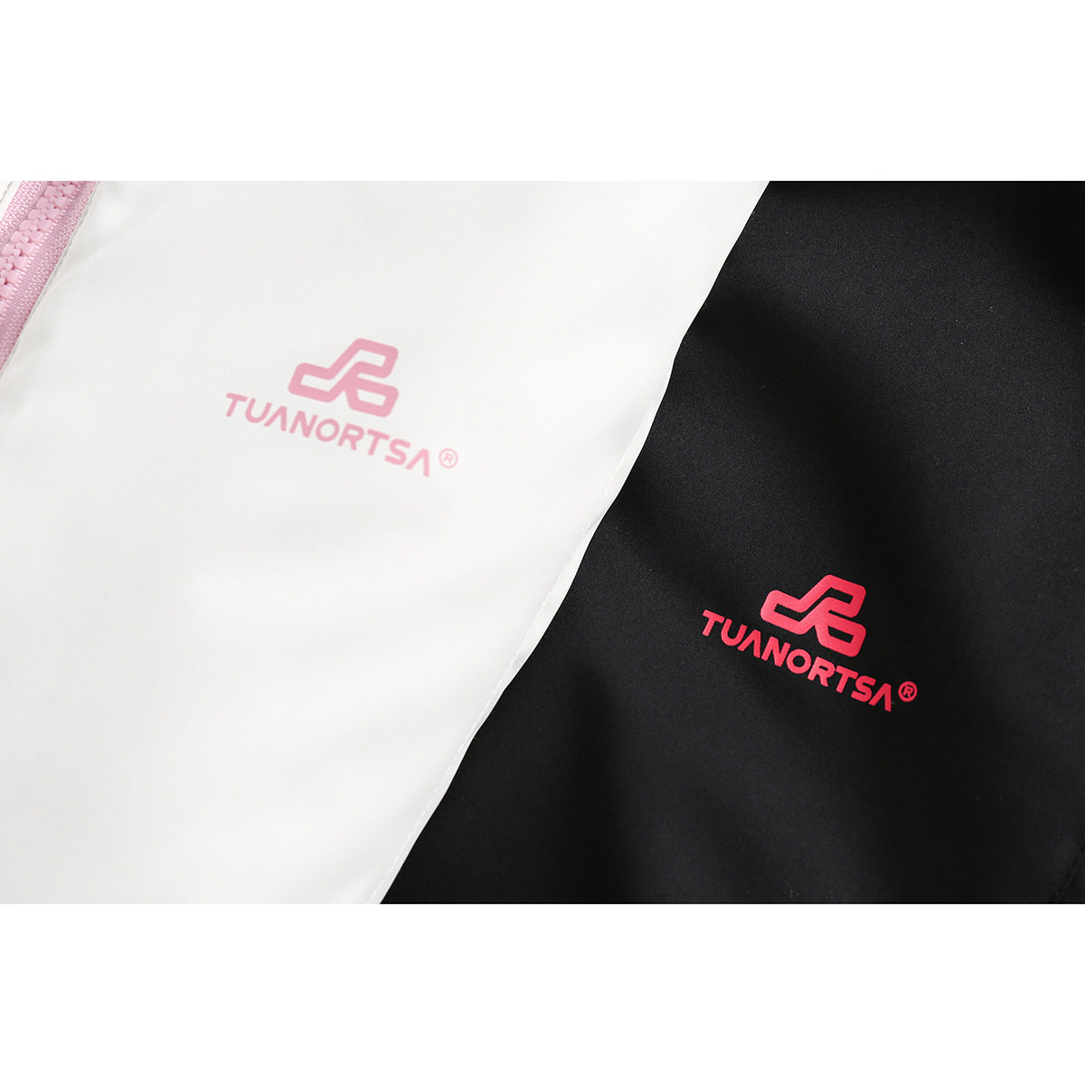 Close-up of white and black jacket fabric with pink and red printed chest logos.