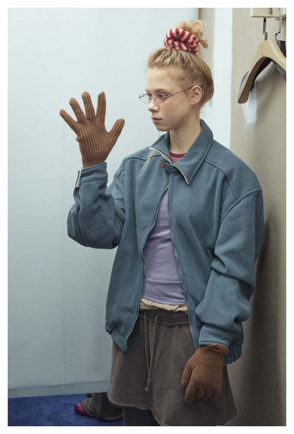 Model wearing an oversized slate-blue zip jacket with a broad collar and gathered cuffs, shown from the front.