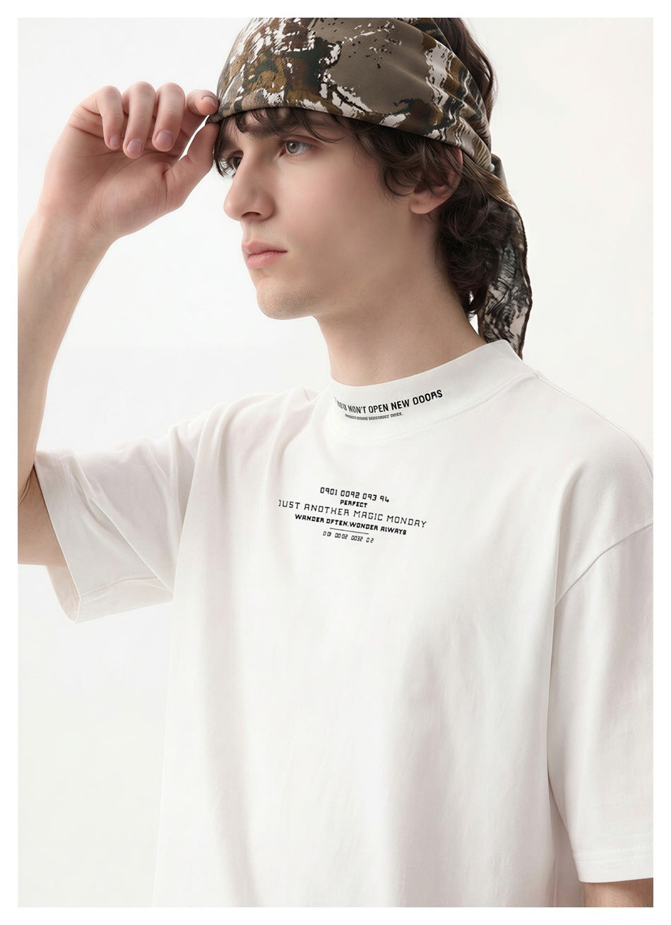 Close-up of a white T-shirt with small black lettering at the chest and collar, worn with a camouflage headscarf.