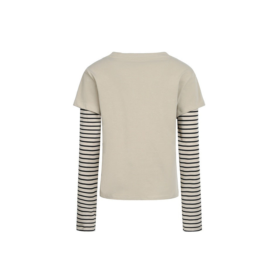 Back view of a beige short-sleeve top layered over long black-and-cream striped sleeves, isolated on white.
