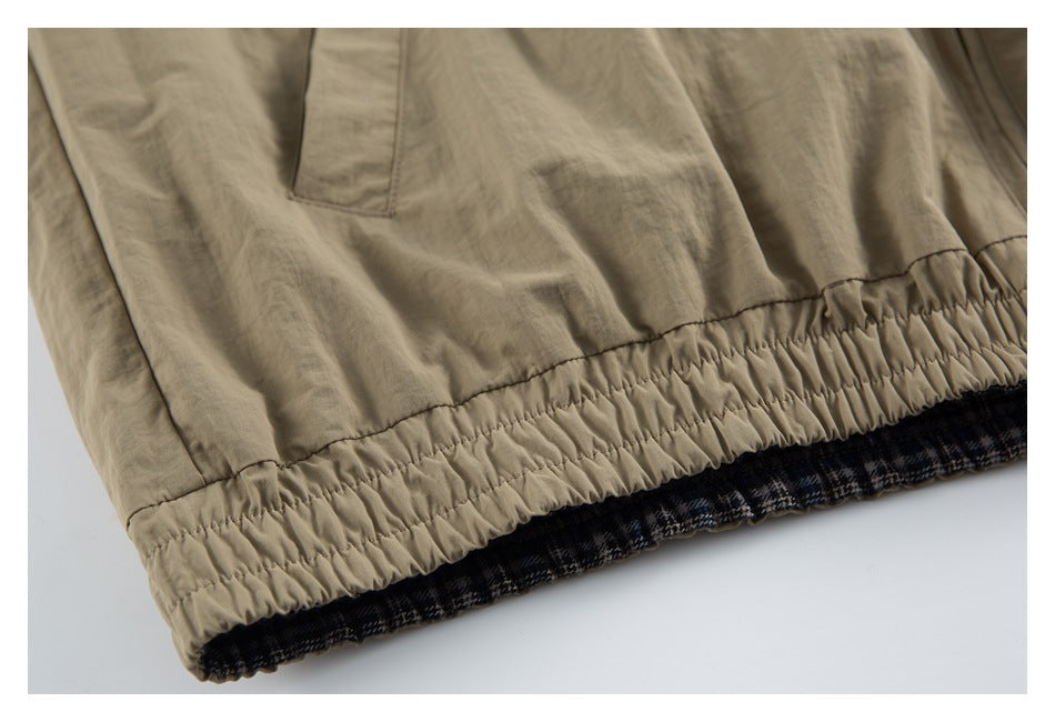 Close-up of the tan jacket's gathered elastic hem with dark plaid lining visible beneath.
