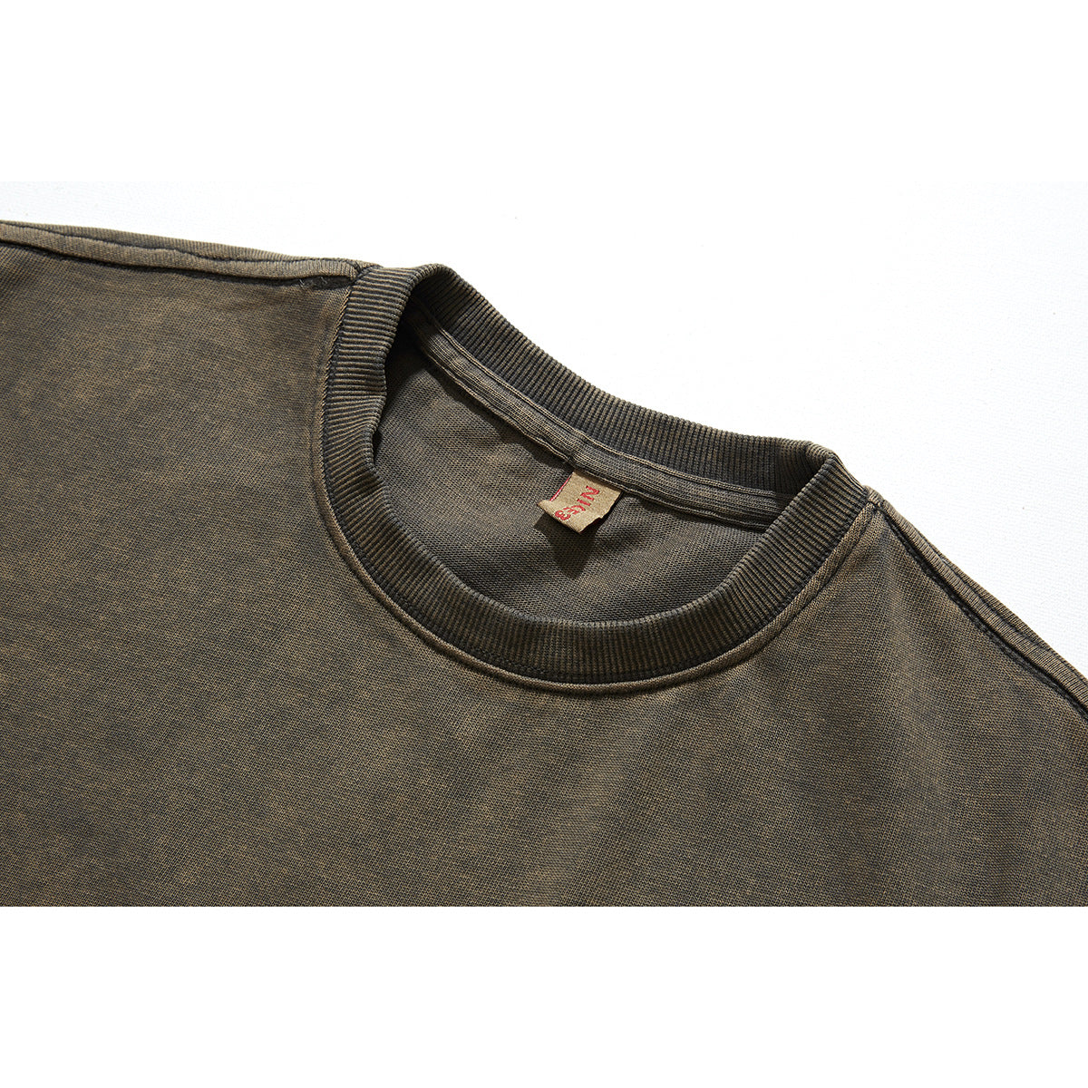 Close-up of a dark olive-brown T-shirt’s ribbed crew neckline, shoulder seam, and small inner neck label.