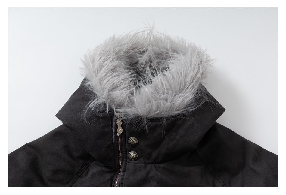 Close-up of the dark jacket's pale fur-trimmed hood, zipper and two buttons.
