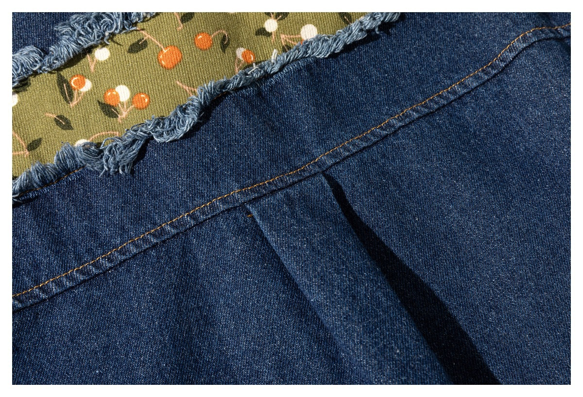 Close-up of a frayed opening in dark blue denim revealing olive fabric with a small floral print.