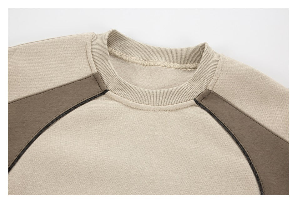 Close-up of a beige sweatshirt's ribbed crew neck and contrasting taupe raglan shoulder panels.