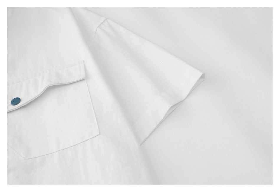 Close-up of the white shirt's short sleeve and pocket with a teal button.
