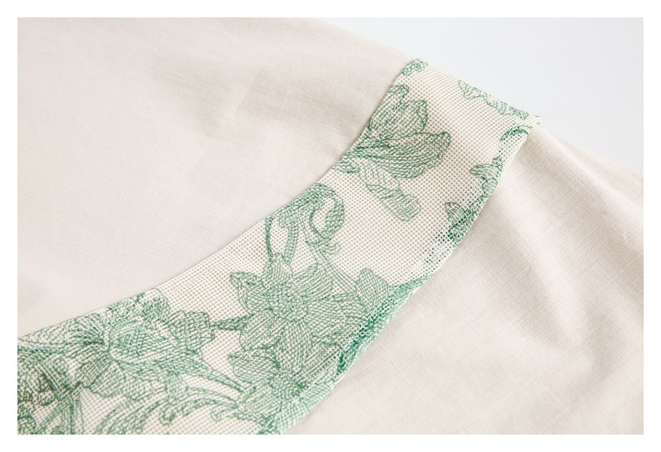 Close-up of a cream garment with a curved green floral patterned trim.