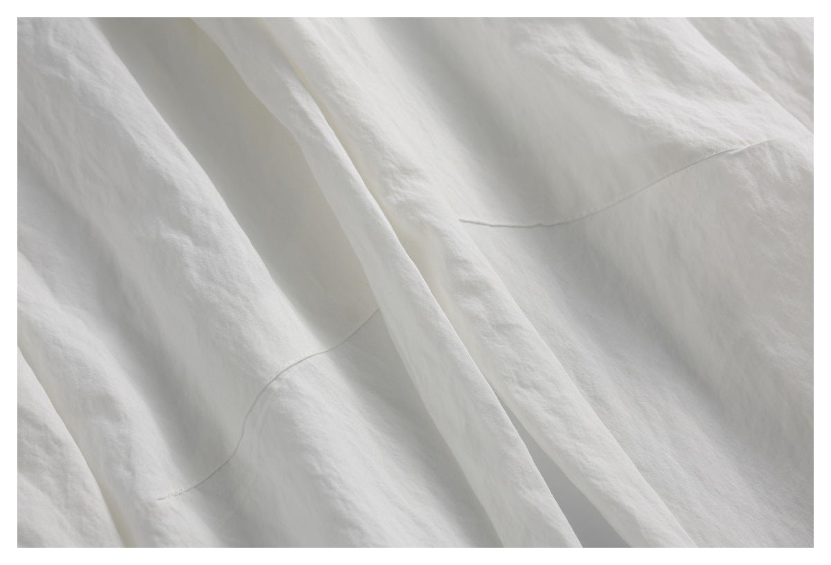 Close-up of off-white trouser fabric with stitched panel seams and overlapping folds.