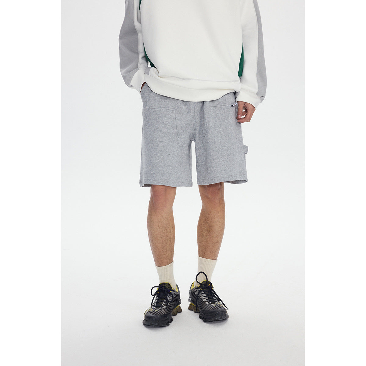 Cropped view of a model wearing gray knee-length shorts with an elastic drawstring waist and side pocket.