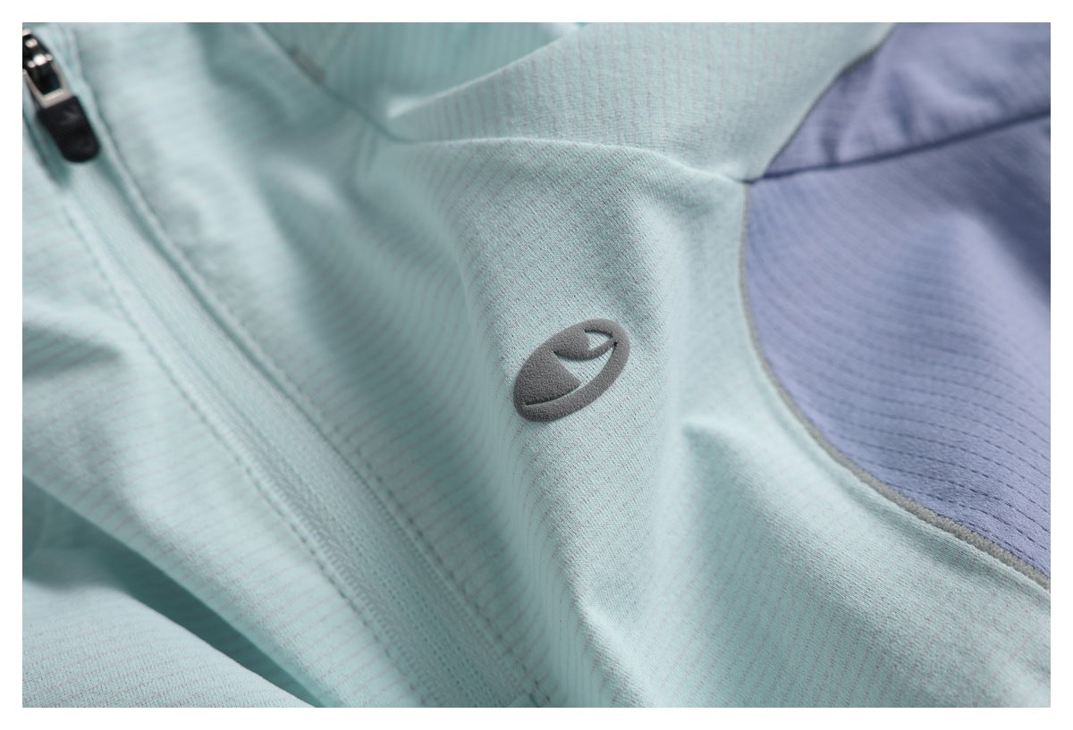 Pale aqua top detail with a small gray chest emblem and a lavender color-block panel.