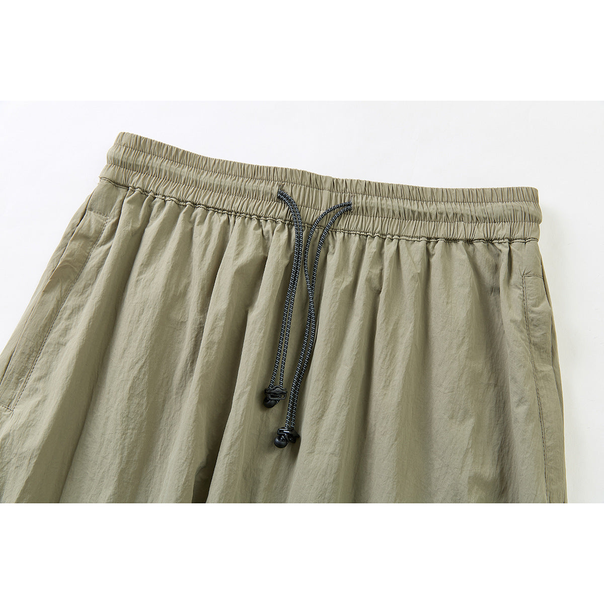Close-up of an olive-khaki garment's gathered elastic waistband and dark drawcords.